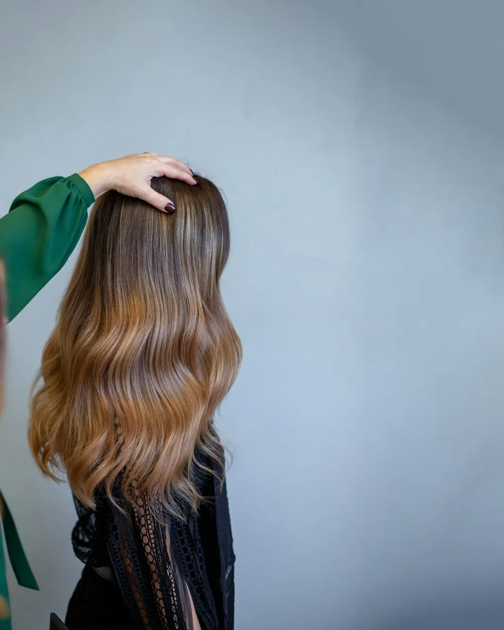 Păr lung, ondulat, cu balayage de la castaniu la caramel, văzut din spate