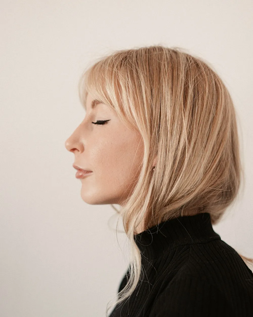 Profil de femeie cu tunsoare bob blond și breton